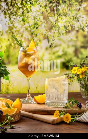 Zwei farbenfrohe Sommercocktails auf einem Holztisch. Starke Seltercocktails mit verschiedenen Früchten: Orange, Zitrone. Outdoor Sommer Par Stockfoto