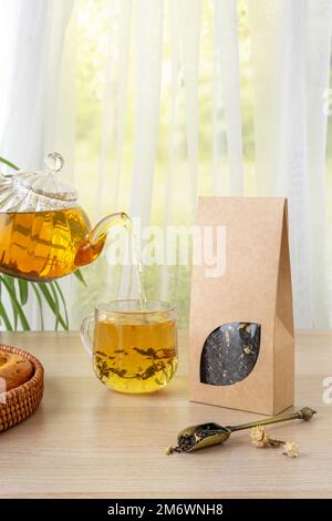 Bio-Teemarkierung und Verpackungsmodell. Grüner Jasmintee in Glas Teekanne auf dem Tisch. Heißer Tee ist in den Glasbechern. Teekanne und Stockfoto