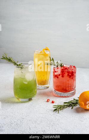 Drei farbenfrohe Sommercocktails in Gläsern auf einem weißen Tisch. Auswahl an frischen Sommergetränken. Rote Sangria-Cocktails, Orangenpunsch Stockfoto