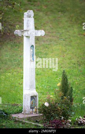 Naiv-Skulptur der madonna auf einem weißen Kreuz eines alten Grabes Stockfoto