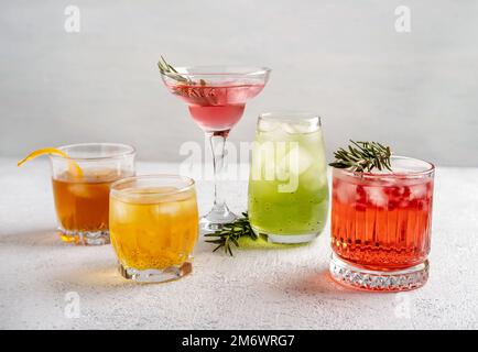 Fünf farbenfrohe Sommercocktails in Gläsern auf einem weißen Tisch. Auswahl an frischen Sommergetränken. Rosa und rote Sangria-Cocktails, o Stockfoto