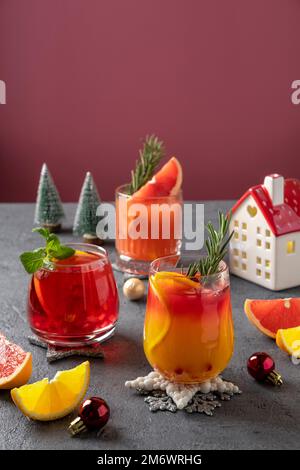 Drei festliche Cocktails mit verschiedenen Zitrusfrüchten. Auswahl an alkoholischen Weihnachtsgetränken. Rosa und rote Sangria-Cocktails, Granatapfel Stockfoto