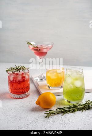 Vier farbenfrohe Sommercocktails in Gläsern auf einem weißen Tisch. Auswahl an frischen Sommergetränken. Rosa und rote Sangria-Cocktails, o Stockfoto