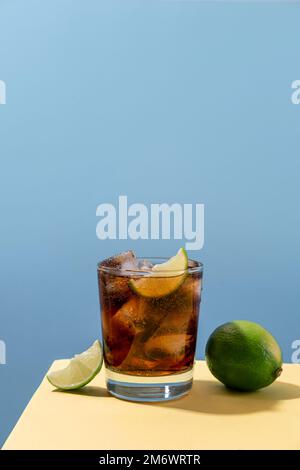 Kuba Libre Alkohol Cocktail mit Limettenscheibe auf blauem Hintergrund. Whiskey-Cola-Cocktail Stockfoto