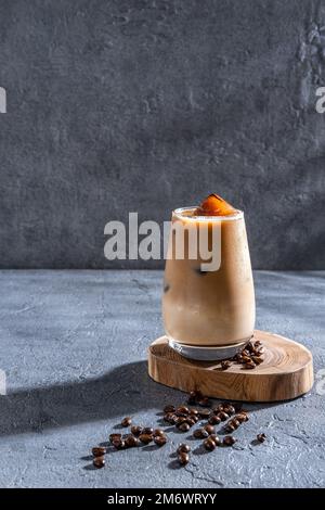 Eiskaffee in einem großen Glas mit Sahne und Kaffeebohnen. Kaltes Kaffeegetränk auf dunklem Hintergrund mit Kopierbereich. Stockfoto
