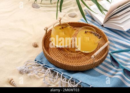 Kalte Ananascocktails auf einem Korbblech am Strand mit weißem Sand. Sommerurlaub und Reisekonzept. Exotische Sommergetränke Stockfoto