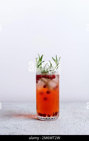 Cranberry und Rosmarin Gin Tonic. Farbenfroher Weihnachtscocktail in Glas auf weißem Tisch. Frische Feiertagsgetränke. Stockfoto