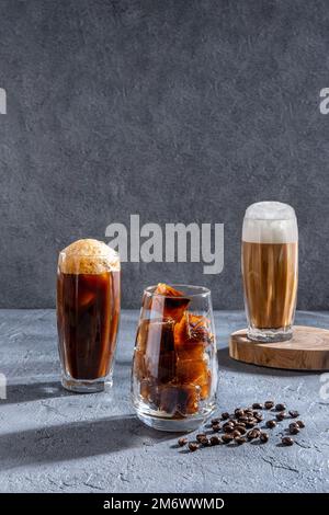 Eiskaffee in einem großen Glas mit Sahne und Kaffeebohnen. Kaltes Kaffeegetränk auf dunklem Hintergrund mit Kopierbereich. Fertig Stockfoto