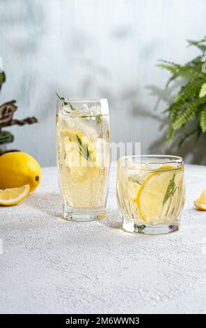 Erfrischende alkoholfreie Cocktails im Sommer. Limonade mit frischem Rosmarin garniert. Sommergetränk mit Mineralwasser und lemo Stockfoto