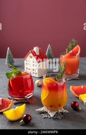 Drei festliche Cocktails mit verschiedenen Zitrusfrüchten. Auswahl an alkoholischen Weihnachtsgetränken. Rosa und rote Sangria-Cocktails, Granatapfel Stockfoto