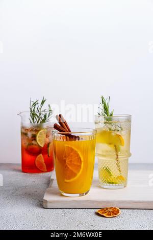 Wassermelone und Limettenpunsch, tropisches Maultier, Orange Gin Tonic. Farbenfrohe Weihnachtscocktails in Gläsern auf einem weißen Tisch. Frischer Holid Stockfoto