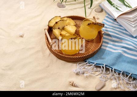 Kalte Ananascocktails auf einem Korbblech am Strand mit weißem Sand. Sommerurlaub und Reisekonzept. Exotische Sommergetränke Stockfoto