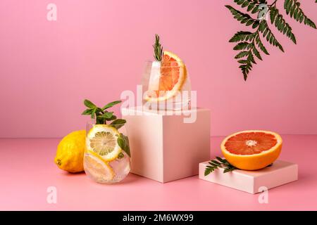 Zwei harte Seltercocktails mit Grapefruit und Zitrone. Erfrischende farbenfrohe Sommergetränke auf pinkfarbenem Hintergrund mit Schattenfarn. Stockfoto