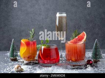 Festliche Cocktails mit verschiedenen Zitrusfrüchten. Auswahl an alkoholischen Weihnachtsgetränken. Rosa und rote Sangria-Cocktails, Champagner, Pomegr Stockfoto