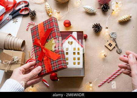 Schlüssel zum Haus mit Schlüsselanhänger auf gemütlichem Zuhause in Geschenkbox mit Weihnachtsdekor-Verpackung. Pack ein Geschenk für Neujahr, Weihnachten. Erstellt Stockfoto