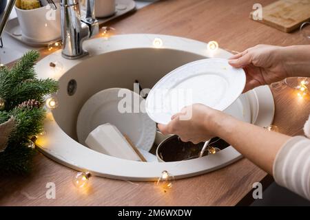 Dreckiges Geschirr im Waschbecken in der Garlandküche, ein Urlaub nach einem Festmahl zu Weihnachten. Die Gäste für das neue Jahr zu beschmutzen, Stockfoto