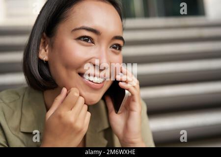 Nahaufnahme eines Porträts von einem asiatischen Mädchen, das mit dem Handy spricht. Eine junge Frau, die telefoniert Stockfoto