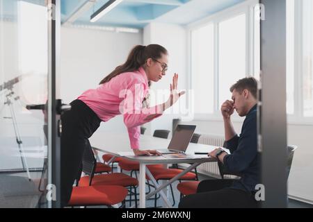 Ein emotionales Paar junger Kollegen, die sich in einem modernen Büro streiten. Geschäftsfrau schreit ihren traurigen Assistenten an, Kopierraum, sid Stockfoto