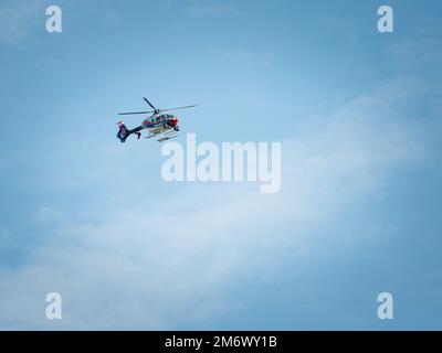 Polizeihubschrauber im Flug, der gegen den blauen Himmel rasiert Stockfoto