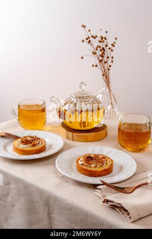 Grüner Tee Oolong in Glasteekanne auf dem Tisch. Heißer Tee ist in den Glasbechern. Stockfoto