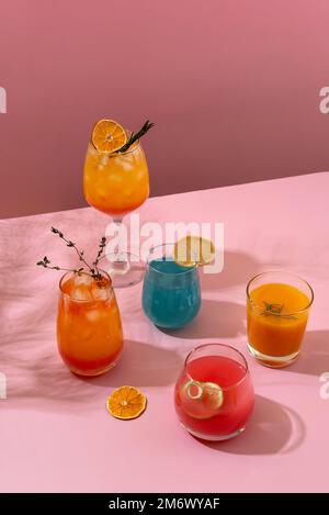 Farbenfrohe tropische Cocktails. Erfrischende, farbenfrohe Sommergetränke auf pinkfarbenem Hintergrund mit Palmenblättern. Getränkekarte an der Bar. Stockfoto