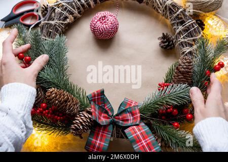 Einen Weihnachtskranz mit eigenen Händen machen. Feiertagsvorbereitung, Hausdekoration, Neujahr Stockfoto