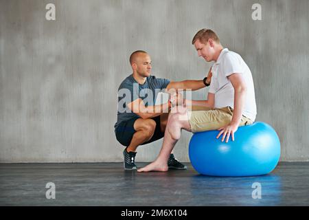 Du schaffst das. Studioaufnahme eines jungen Amputierten, der in einem Fitnessstudio trainiert. Stockfoto