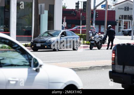 Costa Mesa, Kalifornien, USA - 20. März 2022: Ein Polizist mit Motorrad hält einen Autofahrer während einer Verkehrskontrolle an. Stockfoto