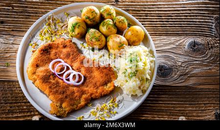 Schweinspanierte Kotelett mit Paniermehl überzogen, serviert mit Kartoffeln und Kohl Stockfoto