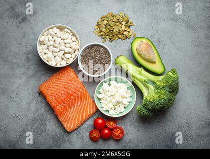 Auswahl gesunder Nahrungsmittel, wenn eine Person Diabetes hat: Lachsfisch, Brokkoli, Avocado, Bohnen, Gemüse, Samen auf grauem B Stockfoto