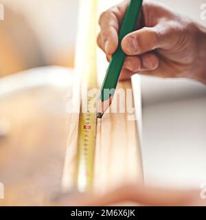 Diese Arbeit erfordert Präzision. Ein Zimmermann, der auf einer Holzplatte Messungen vornimmt. Stockfoto