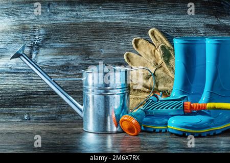 Landwirtschaftliche Werkzeuge, Metallbewässerungskanister und gan auf Gummistiefel sprühen Stockfoto