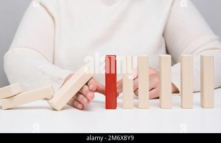 Hand stoppt den Fall von Holzblöcken auf weißem Hintergrund. Konzept einer starken und mutigen Persönlichkeit, die fähig ist, standdi zu überstehen Stockfoto