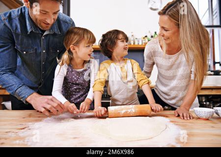 Mache ich es richtig, mom? Eine Familie, die zu Hause Pizza macht. Stockfoto