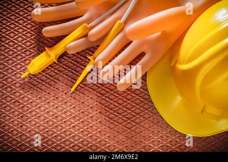 Isolierhandschuhe für Bauhelm Elektrischer Tester auf dielektrischer Matte. Stockfoto