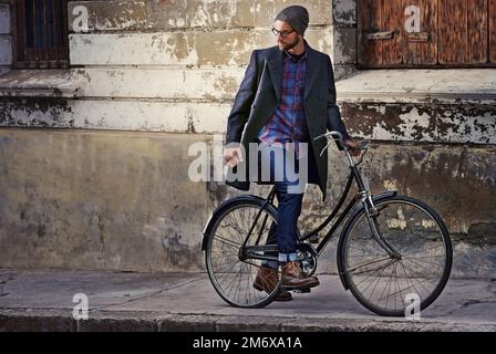 Swag ist für Jungs, Style ist für Männer. Ein hübscher junger Mann in Winterkleidung, der mit seinem Fahrrad steht. Stockfoto