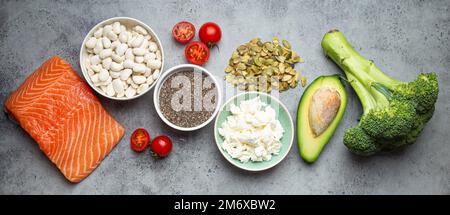 Auswahl gesunder Nahrungsmittel, wenn eine Person Diabetes hat: Lachsfisch, Brokkoli, Avocado, Bohnen, Gemüse, Samen auf grauem B Stockfoto