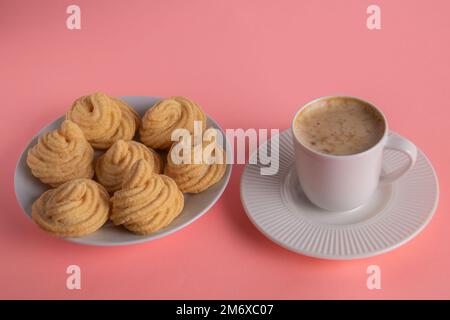 Fotokuchen neben einer Tasse Kaffee auf einer Untertasse auf pinkfarbenem Hintergrund Stockfoto
