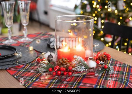 Festlicher Tisch im Wohnzimmer für Weihnachten und Neujahr im Loft-Stil. Weihnachtsbaum, schwarze Teller und Gabeln, gewebtes Nickerchen Stockfoto
