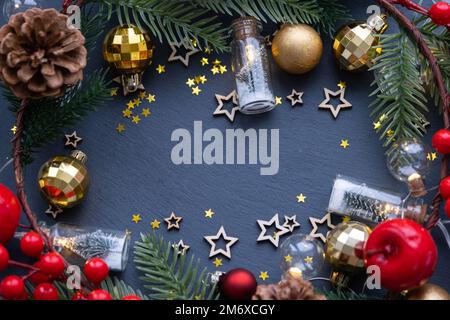 Festlicher Rahmen mit einem Ort für Weihnachten und Silvester-Thementext. Pailletten, Sterne, Girlande, Zapfen, Bälle auf einem schwarzen Steinrücken Stockfoto