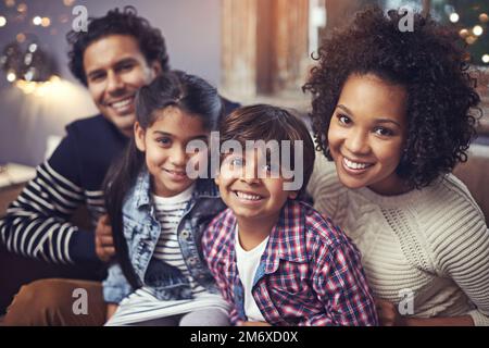 Die Familie ist das, was wirklich zählt. Porträt einer glücklichen vierköpfigen Familie, die zu Hause auf dem Sofa sitzt. Stockfoto