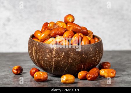 Frische, rohe Silberbeeren auf dunklem Hintergrund. Silverberry in einer Kokosnussschale. Oleaster- oder russische Oliven (Elaeagnus). Schließen Stockfoto