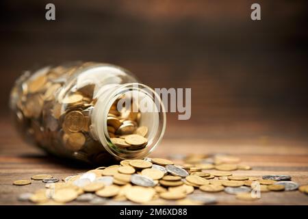 Glasbehälter mit goldenen Münzen Stockfoto