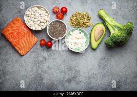 Auswahl gesunder Nahrungsmittel, wenn eine Person Diabetes hat: Lachsfisch, Brokkoli, Avocado, Bohnen, Gemüse, Samen auf grauem B Stockfoto