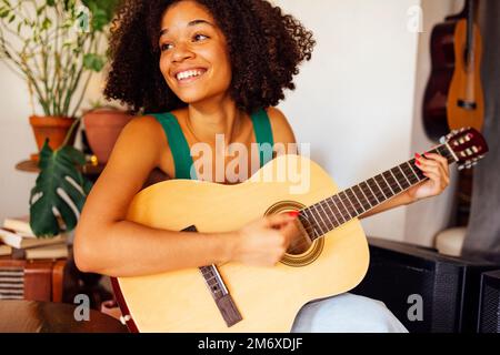 Afro-amerikanische junge Frau, die Akustikgitarre spielt. Stockfoto