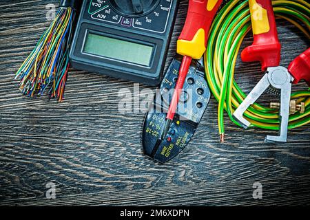 Elektrokabeltester Schraubendreher gerollte Kabelisolierzangen auf Holzplatte. Stockfoto