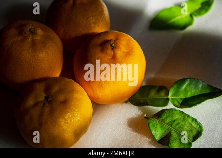 Orangenfrüchte mit Licht und Schatten auf weißem Hintergrund Stockfoto