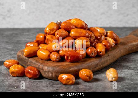 Frische, rohe Silberbeeren auf dunklem Hintergrund. Silverberry auf einer Holzpräsentationstafel. Oleaster- oder russische Oliven (Elaeagnus). Schließen Stockfoto