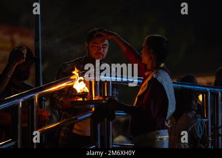 Haridwar, Indien - Okt. 2022: Porträt des männlichen hindu-Priesters, der den Fluss Ganges aarti mit Feuerlicht in der Hand am triveni ghat anbetet, um den Fluss ganga anzubeten. Stockfoto