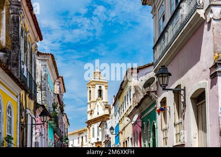 Alte Häuser mit bunten Fassaden und historischer Kirchturm in Pelourinho Stockfoto